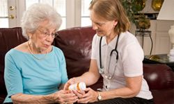 An aide helps an assisted living resident with her medications.