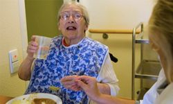 A nursing home resident gets help with her meal.