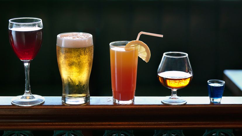 From left to right, glasses of red wine, beer, a cocktail, whiskey and a shot of blue liqueur.