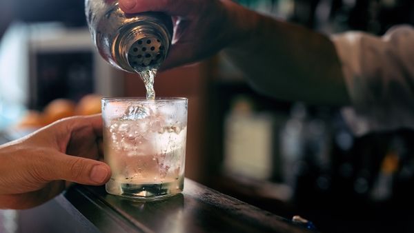 Men pouring drinks at bar in drink establishment.