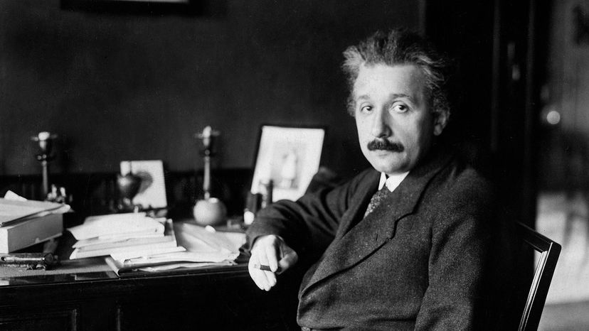 Albert Einstein sits at his desk.