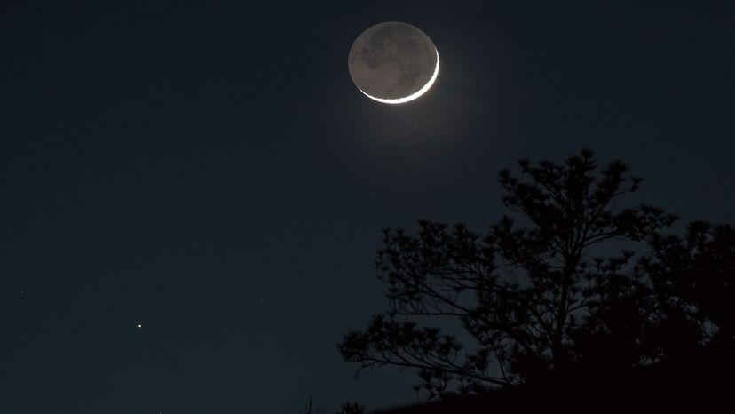 A waxing crescent moon in contrast to Aldebaran in the night sky.