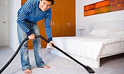 man vacuuming under bed