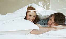 couple in bed, swaddled in white bedding