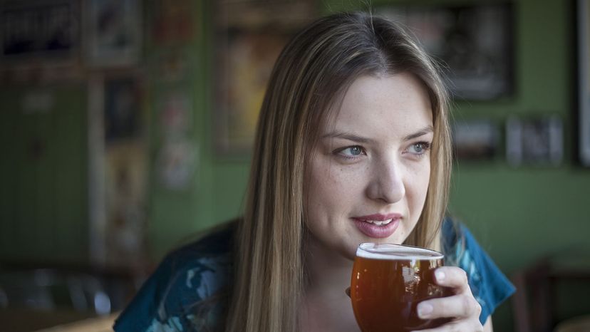 A woman drinks beer.