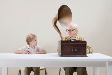 Child with MP3 player sitting with elderly woman with victrola.