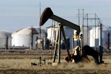 A pump jack works in a field near a Valero refinery in Sunray, Texas.