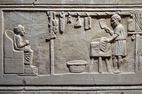 A butcher cuts up meat for a client in his shop in ancient Rome.