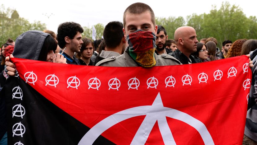A masked demonstrator displays an anarchy flag close to the blocked street leading to Spain's parliament during an anti-government demonstration in Madrid in 2013. JAVIER SORIANO/AFP/Getty Images