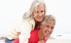 Senior Man Giving Woman Piggyback On Winter Beach