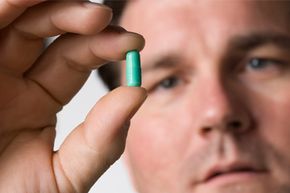 Man looks at pill in hand