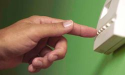 Finger pressing a button on a thermostat.
