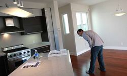 A man inspecting the kitchen area of an empty rental apartment.