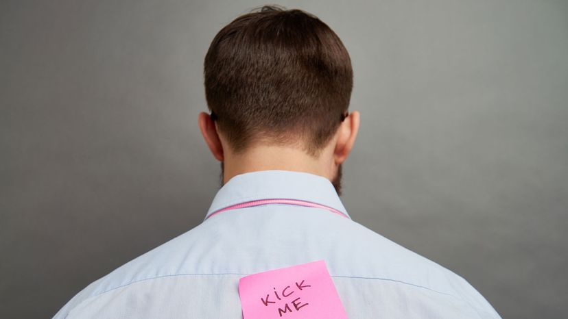 man with "kick me" sign