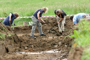 Teamworking outdoors to cultivate the soil.