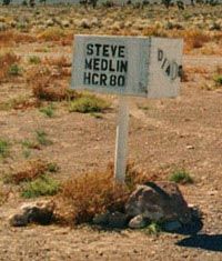 A white mailbox on a white post in the desert, with "STEVE MEDLIN HCR80" painted on it in black.