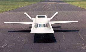 The white plane, Tacit Blue, sits on a tarmac runway.