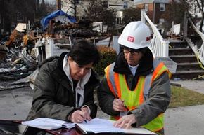 玛莎·米利塔诺(左)签署了一份进入权表格，授权美国陆军工程兵团在飓风桑迪后拆除她的家。＂width=