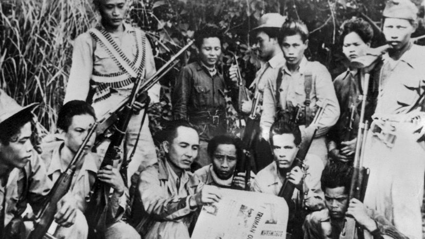 Luis Taruc (C) , rebel leader of the Huks and founder of the communist struggle in the Philippines, reads the newspaper while his partisans look on. The CIA wanted Taruc and his men gone. AFP via Getty Images