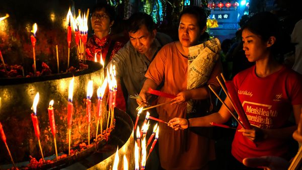 Men of diverse cultures united by a single candle flame.