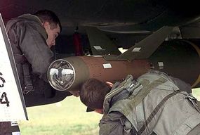 An F-15E Strike Eagle pilot and a weapons system officer inspect a GBU-28 laser-guided bomb.