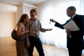 Real estate agent giving house keys to couple.