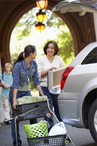 mother and daughter unload trunk of car