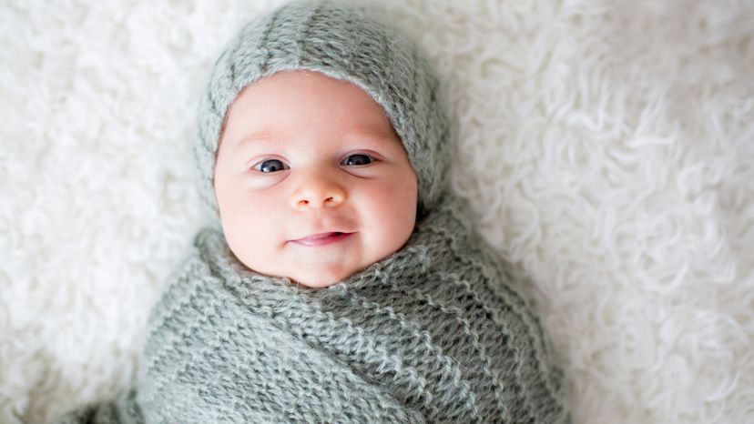 Cute newborn baby boy with knit grey hat and blanket