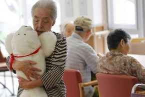 A retirement home resident cuddles a Paro. The FDA considers the faux harp seal a Class II medical device.
