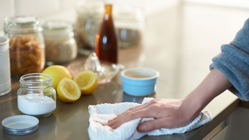 Woman cleaning a kitchen worktop with natural cleaning products lemon, bicarbonate of soda and vinegar.