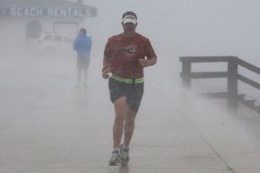 约翰·哈里斯参加三项全能运动训练,在风雨中运行像Alex飓风的影响感到德州海岸6月30日,2010年。”width=