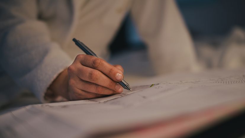 A woman writing with a ballpoint pen at night.