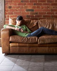 A woman with a mobile phone relaxes on a couch.