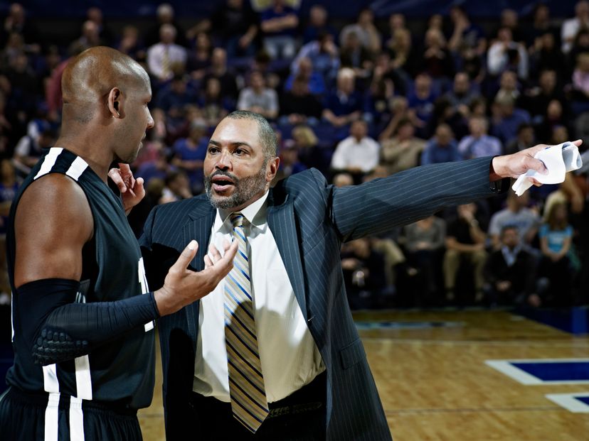 Professional basketball coach giving directions to player in crowded arena during game