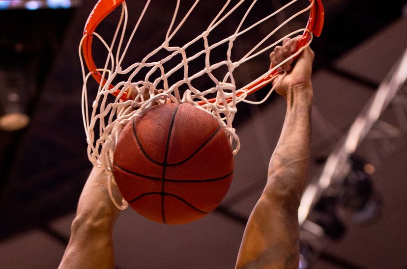 Male basketball player dunks the ball with two hands.