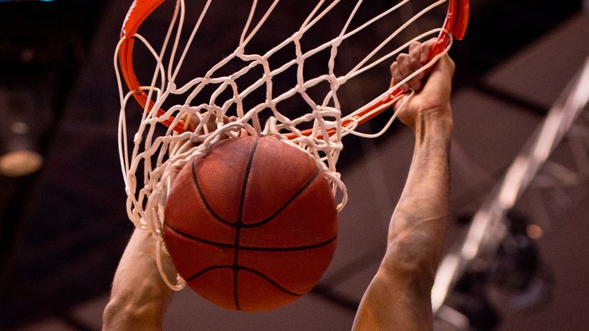 Basketball player dunks the ball with two hands.