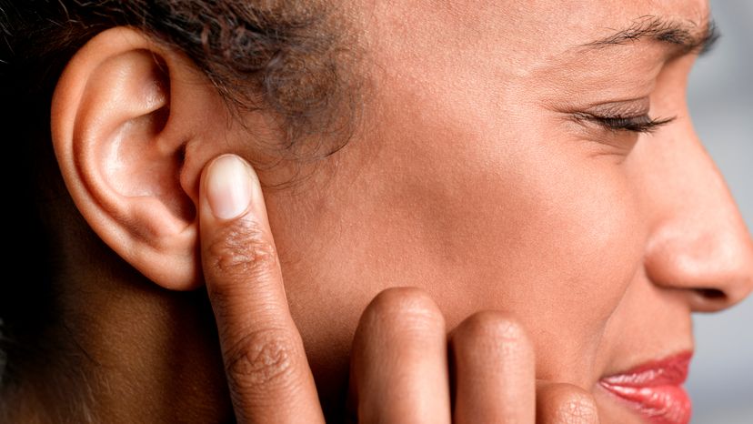 Close up of a woman with holding ear with ear barotrauma pain 