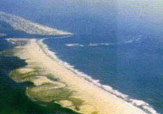 Changes in Assateague Island as a result of accelerated erosion from the man-made rock jetties of Ocean City Inlet (top: photo of the inlet, bottom: map of the area with outline showing the position of the island in 1849).