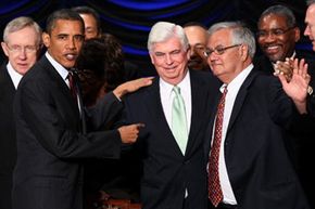 After signing the Wall Street reform bill they co-wrote into law on July 21, 2010, President Barack Obama congratulates Sens. Christopher Dodd and Barney Frank.