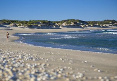 Woman walking along coast in Hawk's Nest, New South Wales, Australia