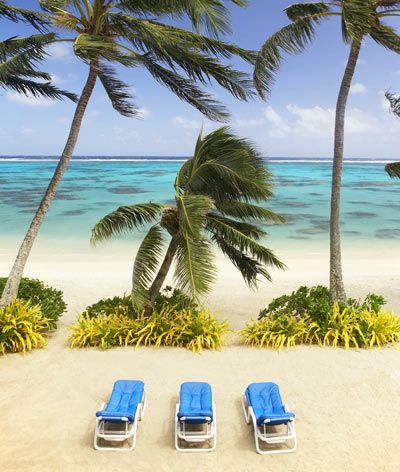 Three sunloungers on beach with palm trees in the Cook Islands