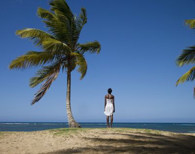 Woman standing by palm tree on Samana Peninsula, Dominican Republic