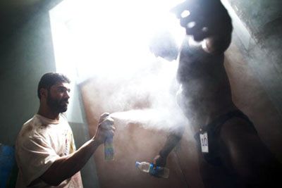 a competitor in the annual Mr. Afghanistan body building competition in Kabul gets a spray tan