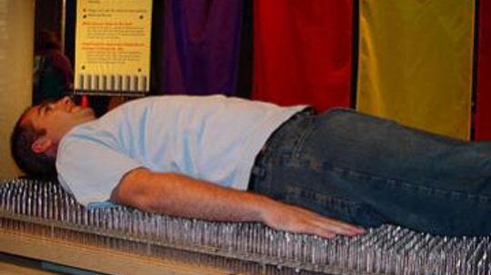 How can someone lie on a bed of nails without getting hurt?