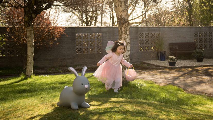 little girl collecting easter eggs with big rabbit