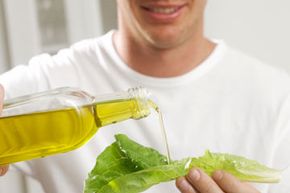 man pouring salad oil on lettuce leaf