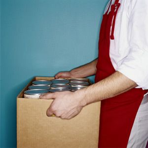 Clerk carrying box of canned goods, mid section, side view