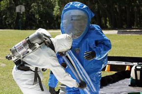 Firefighters help one another remove hazardous material protective suits to avoid self-contamination after responding to a simulated chemical attack during an anti-terrorism force protection exercise.