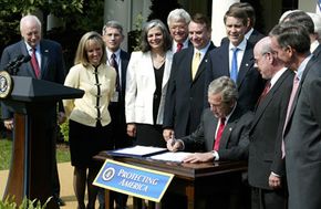 Members of Congress are pleased when President Bush autographs the "Project Bioshield" legislation.”border=