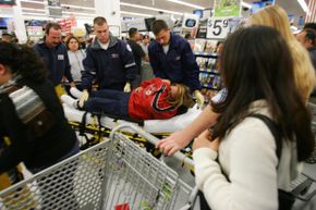 2005年黑色星期五，在加州杜阿尔特的沃尔玛超市，急救人员正在帮助一名购物者，他在开门后不久就摔倒了。“border=